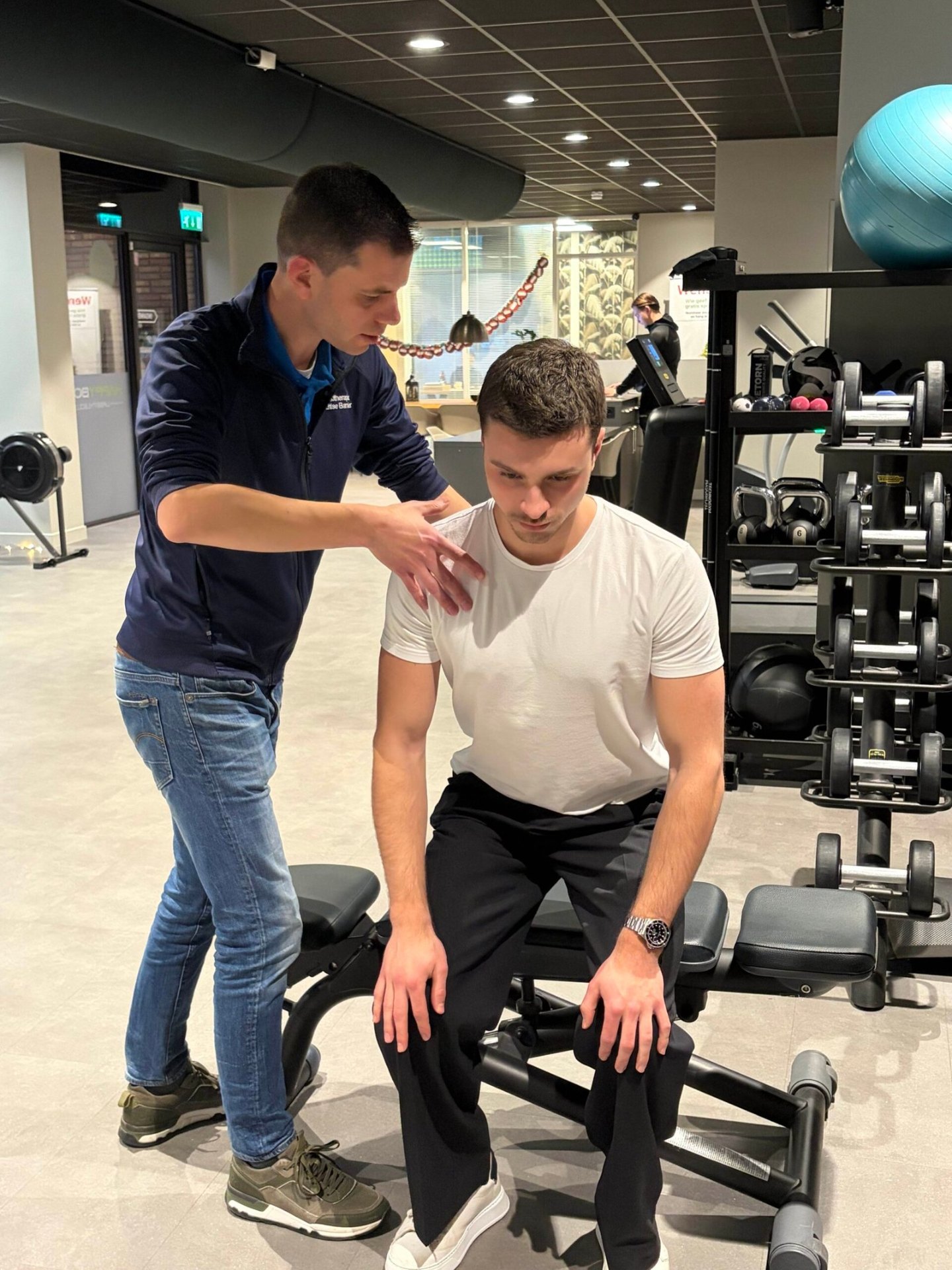 Fysiotherapeut begeleidt patiënt bij schouderoefening in de oefenzaal van Fysiotherapie Strijp-S Eindhoven